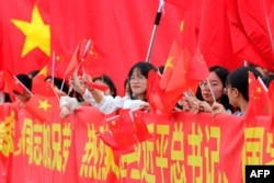 Masyarakat mengibarkan bendera nasional China dan Vietnam menjelang kedatangan Presiden China Xi Jinping dan istrinya Peng Liyuan di Bandara Internasional Noi Bai di Hanoi pada 12 Desember 2023. (Foto: AFP)