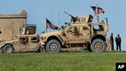 A fighter, second from right, of U.S-backed Syrian Manbij Military Council stands next to U.S. humvee at a U.S. outpost north of Manbij town, Syria, March 29, 2018, .