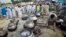 FILE - A Pakistani non-governmental humanitarian organization volunteer (front) adjusts a cooking fire as locals line up to receive meals in Nowshera, in Pakistan's northwest Khyber-Pakhtunkhwa Province, Sept. 10, 2010. Foreign-funded local organizations in northwestern Pakistan provide humanitarian and emergency assistance, including health, education, and food distribution, to more than two million people who have been displaced by ongoing Pakistani military operations against militant groups.
